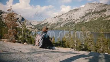 后景游客女孩坐在大石头的边<strong>缘</strong>，男人上<strong>来</strong>坐在她旁边的约塞米蒂公园湖慢动作